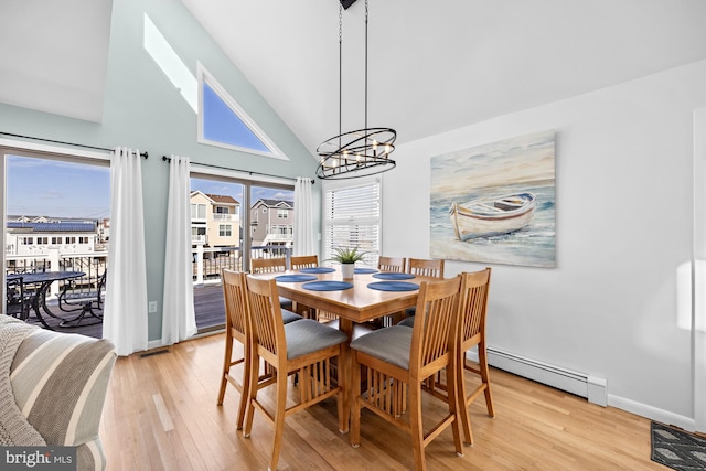 dining space with a notable chandelier, high vaulted ceiling, light wood-type flooring, and a baseboard heating unit