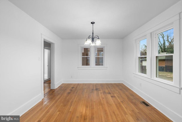 unfurnished dining area featuring a notable chandelier and light hardwood / wood-style flooring