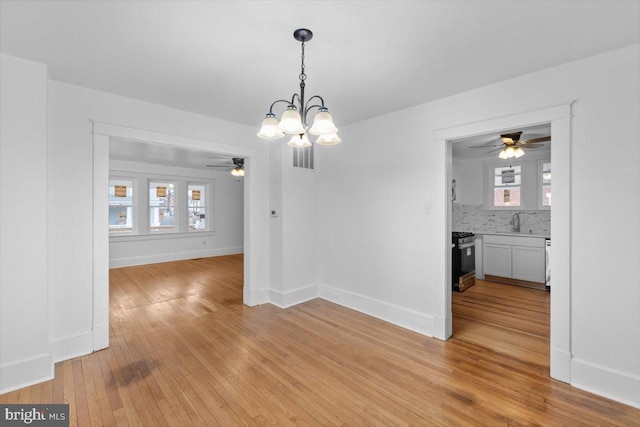 unfurnished dining area with sink, light hardwood / wood-style flooring, and a chandelier