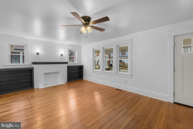 unfurnished living room with a brick fireplace, light hardwood / wood-style flooring, and ceiling fan