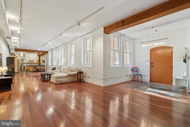 unfurnished living room with brick wall, wood-type flooring, and beam ceiling