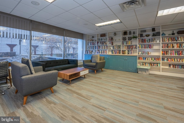 interior space featuring bookshelves, carpet, visible vents, and a drop ceiling