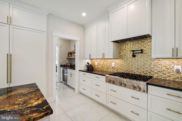 kitchen featuring wine cooler, stainless steel gas cooktop, dark stone counters, decorative backsplash, and white cabinets