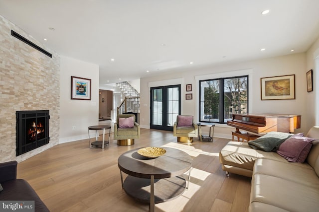 living room with a fireplace, french doors, and light wood-type flooring