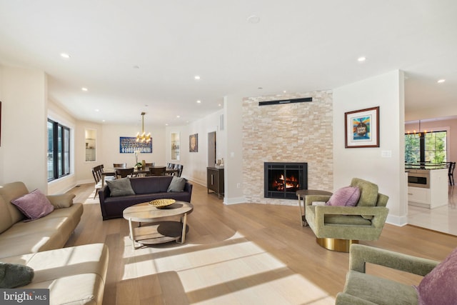 living room with a fireplace, light hardwood / wood-style flooring, and a notable chandelier