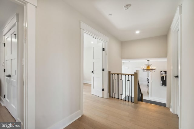 hallway with a notable chandelier and light hardwood / wood-style floors