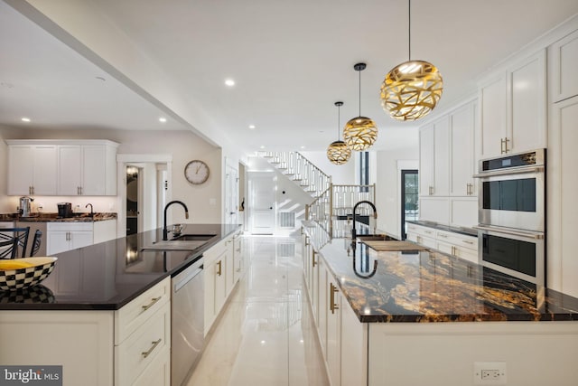 kitchen featuring a spacious island, white cabinetry, appliances with stainless steel finishes, and decorative light fixtures