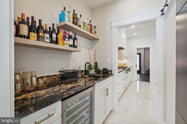 bar featuring white cabinetry, sink, dark stone countertops, and beverage cooler