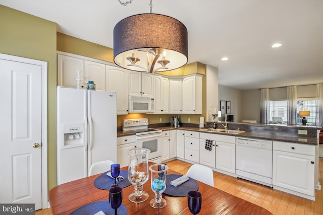 kitchen with sink, white cabinetry, hanging light fixtures, light hardwood / wood-style flooring, and white appliances