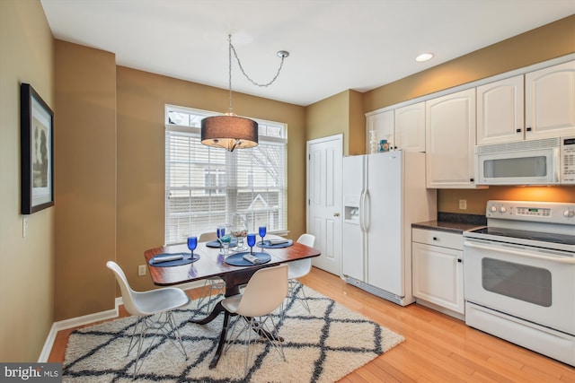 kitchen with white cabinetry, pendant lighting, white appliances, and light hardwood / wood-style flooring