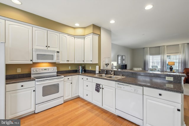 kitchen featuring sink, light wood-type flooring, kitchen peninsula, white appliances, and white cabinets