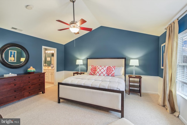 carpeted bedroom with ceiling fan, lofted ceiling, and ensuite bathroom