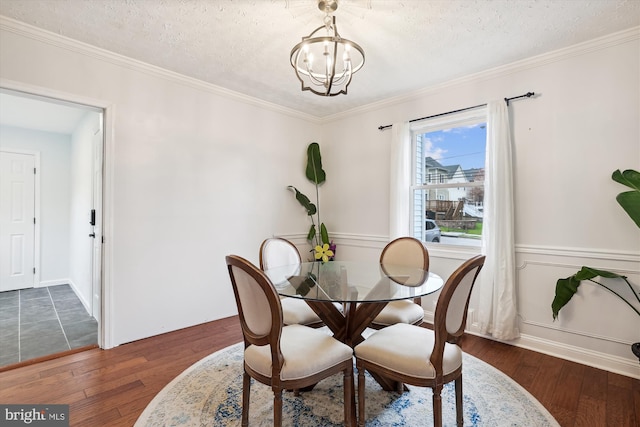 dining area featuring ornamental molding, dark wood-type flooring, a textured ceiling, and a chandelier