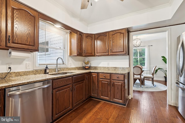 kitchen with appliances with stainless steel finishes, sink, ornamental molding, light stone counters, and dark wood-type flooring