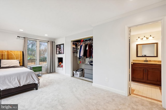 carpeted bedroom with sink, crown molding, a closet, and ensuite bathroom