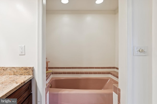 bathroom featuring ornamental molding, vanity, and a bath