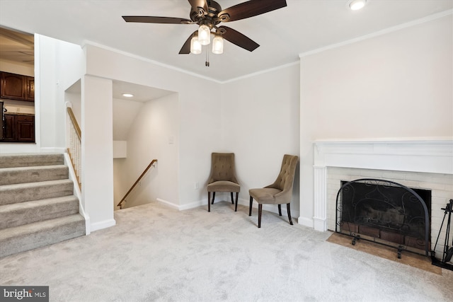 sitting room with ornamental molding, a brick fireplace, light colored carpet, and ceiling fan