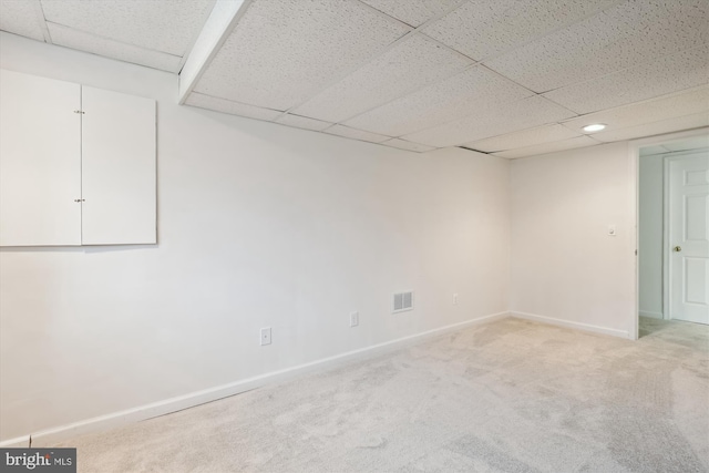 basement with light colored carpet and a paneled ceiling