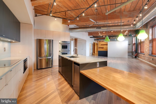 kitchen with pendant lighting, stainless steel appliances, sink, and an island with sink