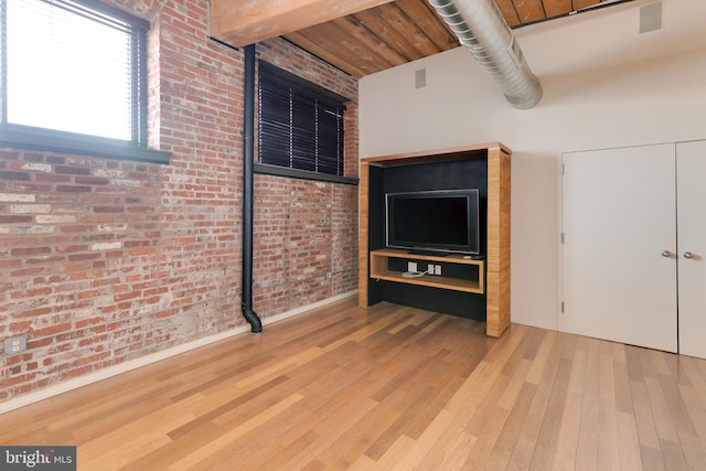 unfurnished bedroom featuring brick wall and hardwood / wood-style floors