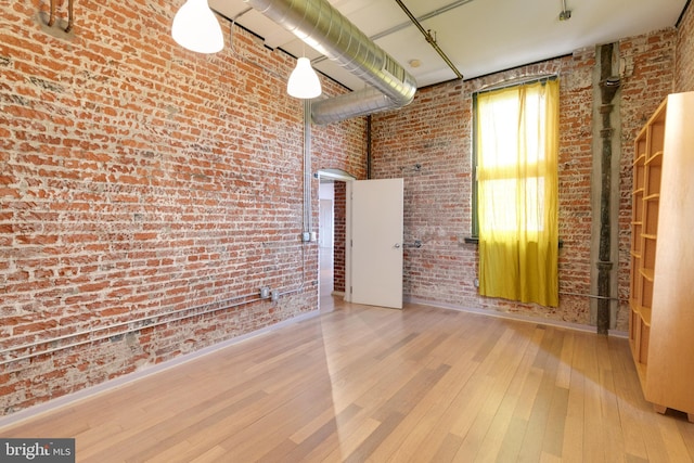 empty room featuring light hardwood / wood-style flooring and brick wall