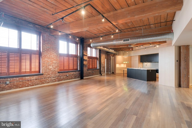 unfurnished living room with beamed ceiling, brick wall, wooden ceiling, and light hardwood / wood-style flooring