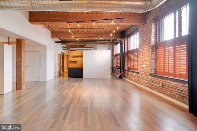 empty room with beamed ceiling, brick wall, wooden ceiling, and light hardwood / wood-style floors