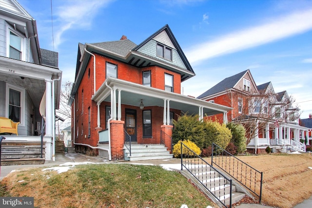 victorian house with a front yard and a porch