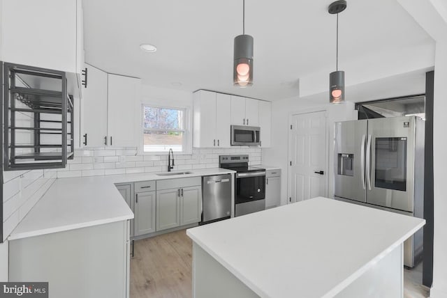 kitchen featuring appliances with stainless steel finishes, decorative light fixtures, gray cabinets, and sink