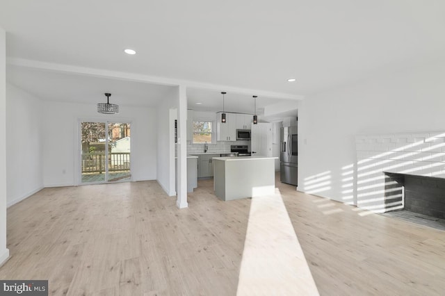 unfurnished living room with beamed ceiling, sink, and light wood-type flooring