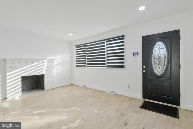 entrance foyer featuring a brick fireplace and light wood-type flooring