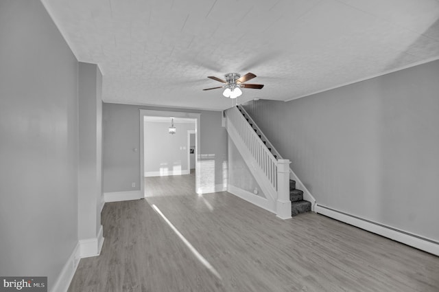 unfurnished living room with a baseboard radiator, ceiling fan with notable chandelier, and light hardwood / wood-style flooring