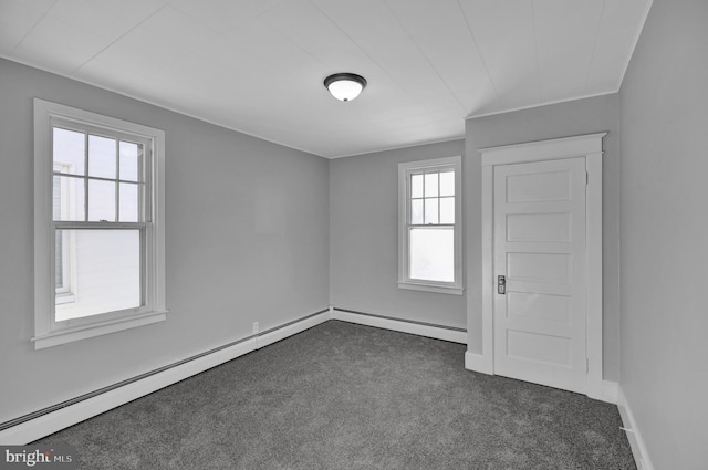 empty room with a baseboard heating unit and dark carpet