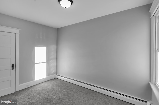 empty room with a baseboard heating unit and carpet flooring