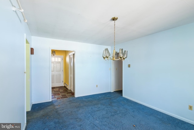 spare room featuring dark carpet and an inviting chandelier