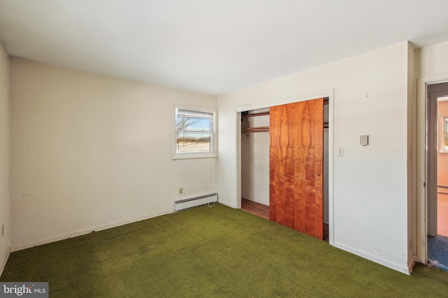 unfurnished bedroom featuring dark colored carpet, baseboard heating, and a closet