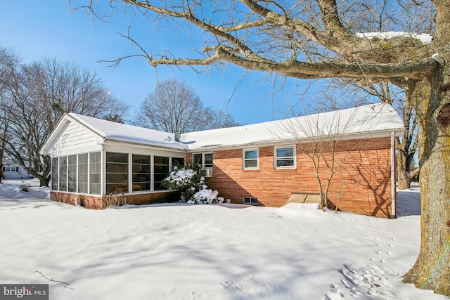 snow covered back of property featuring cooling unit and a sunroom