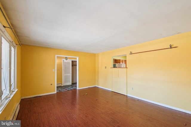 empty room featuring dark wood-type flooring and a baseboard radiator