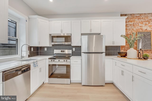 kitchen with sink, decorative backsplash, white cabinets, and appliances with stainless steel finishes