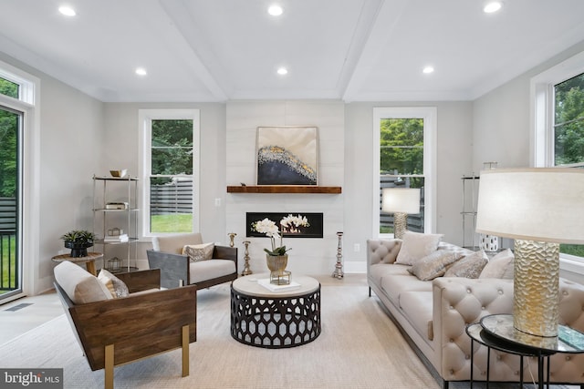 living room with beam ceiling, a large fireplace, a wealth of natural light, and light hardwood / wood-style floors