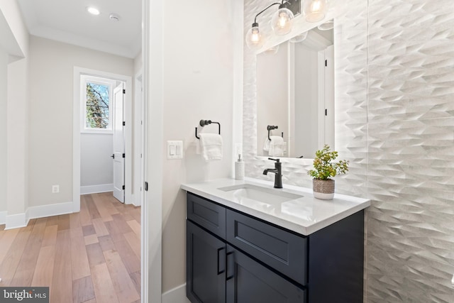 bathroom with crown molding, vanity, and hardwood / wood-style floors