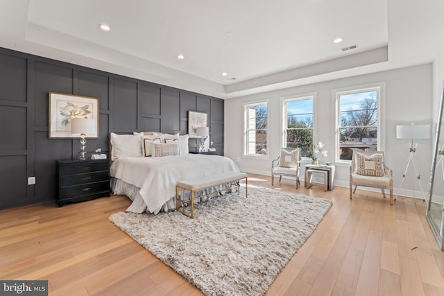 bedroom featuring a raised ceiling and light hardwood / wood-style flooring