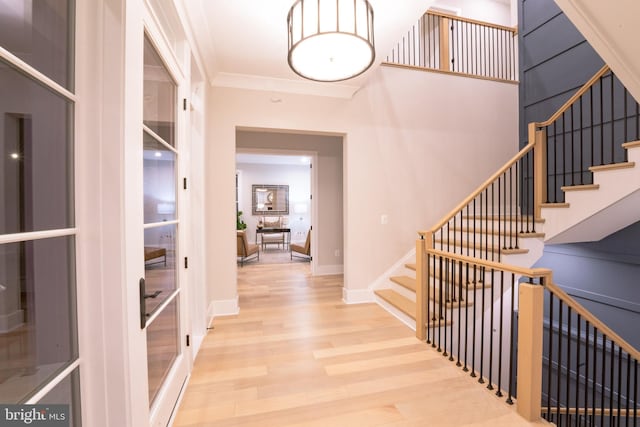 foyer entrance with crown molding and light wood-type flooring