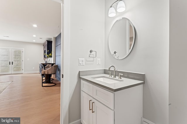 bathroom with wood-type flooring, vanity, and french doors