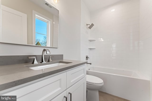 full bathroom with vanity, tiled shower / bath combo, and toilet