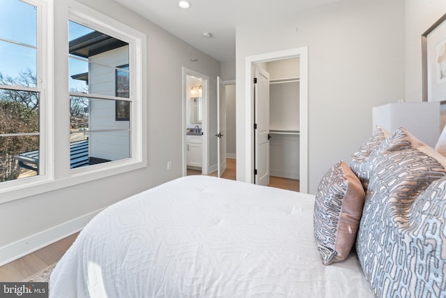 bedroom featuring hardwood / wood-style flooring, a walk in closet, and ensuite bath