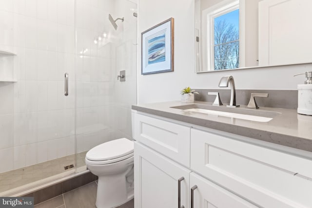 bathroom featuring vanity, toilet, and a shower with door