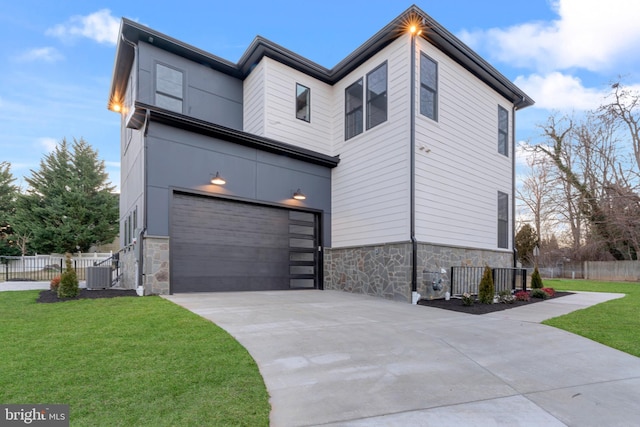 contemporary house with a garage, a front yard, and central air condition unit