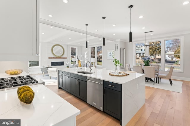 kitchen featuring sink, light stone counters, decorative light fixtures, stainless steel appliances, and a large island