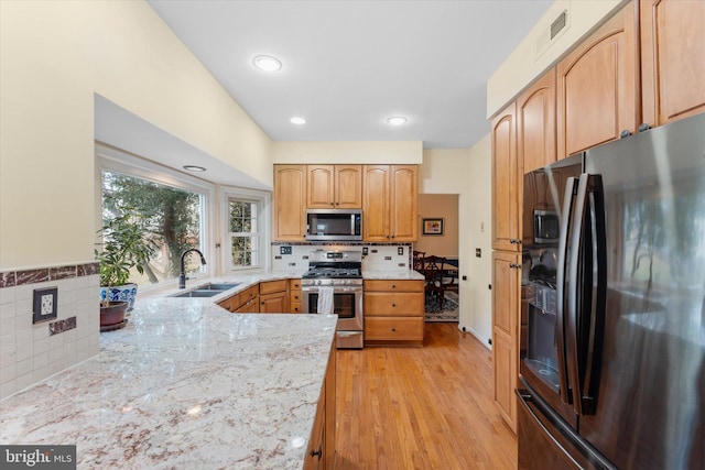 kitchen with light brown cabinetry, sink, decorative backsplash, stainless steel appliances, and light wood-type flooring